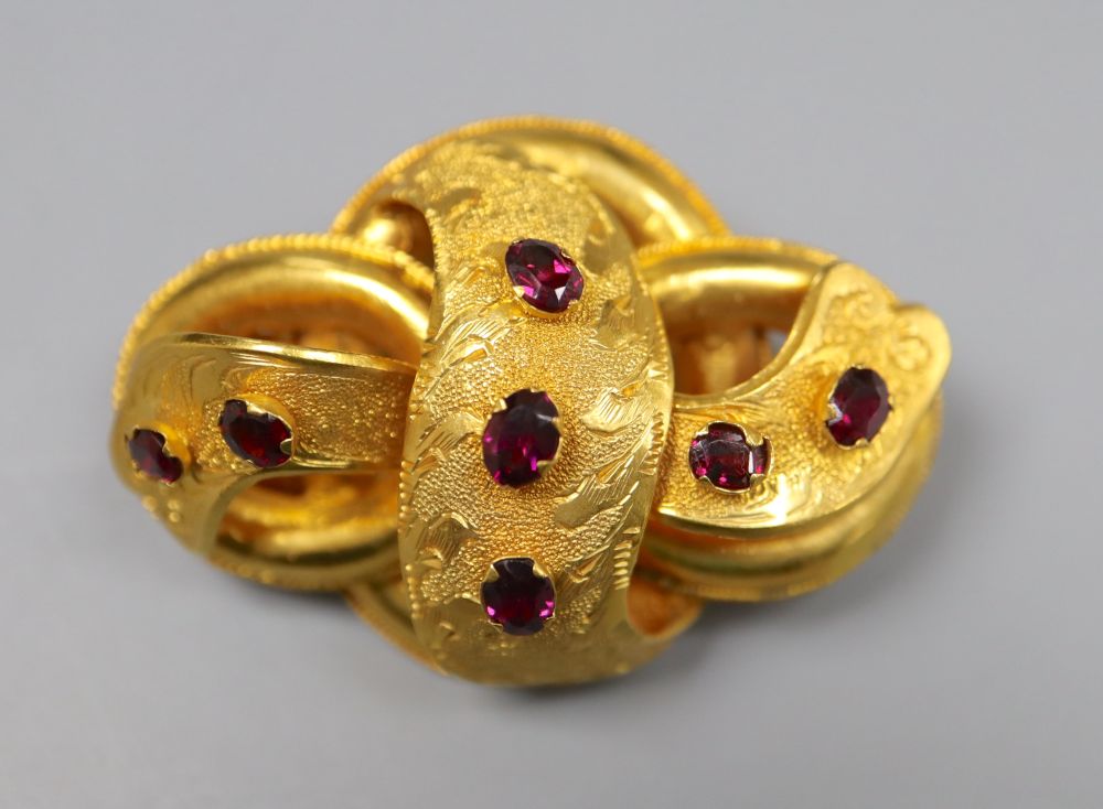 A Victorian yellow metal and seven stone garnet set scroll brooch, 47mm, gross 13.1 grams.